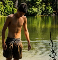 a young man standing in front of a body of water